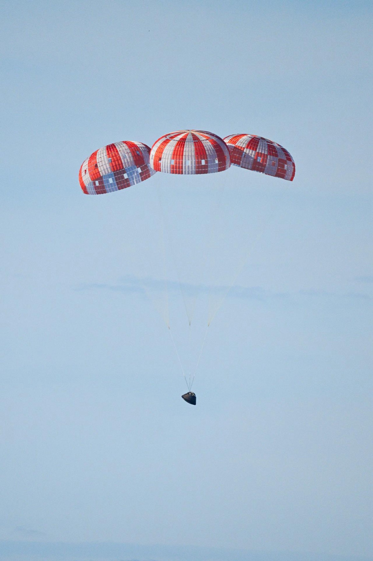 Parachutes deploying above NASA's Orion spacecraft before splashdown in the Pacific Ocean at the end of Artemis II