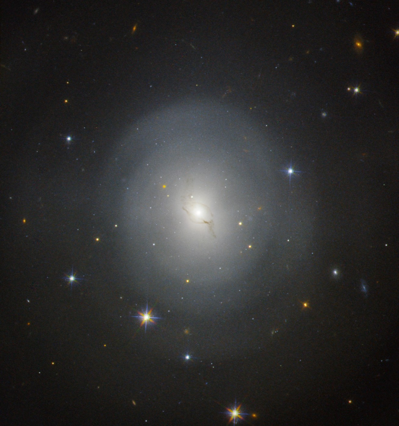 Hubble image of the lenticular galaxy NGC 4993, a soft glowing ellipse, with the kilonova from the GW170817 neutron star merger near its core