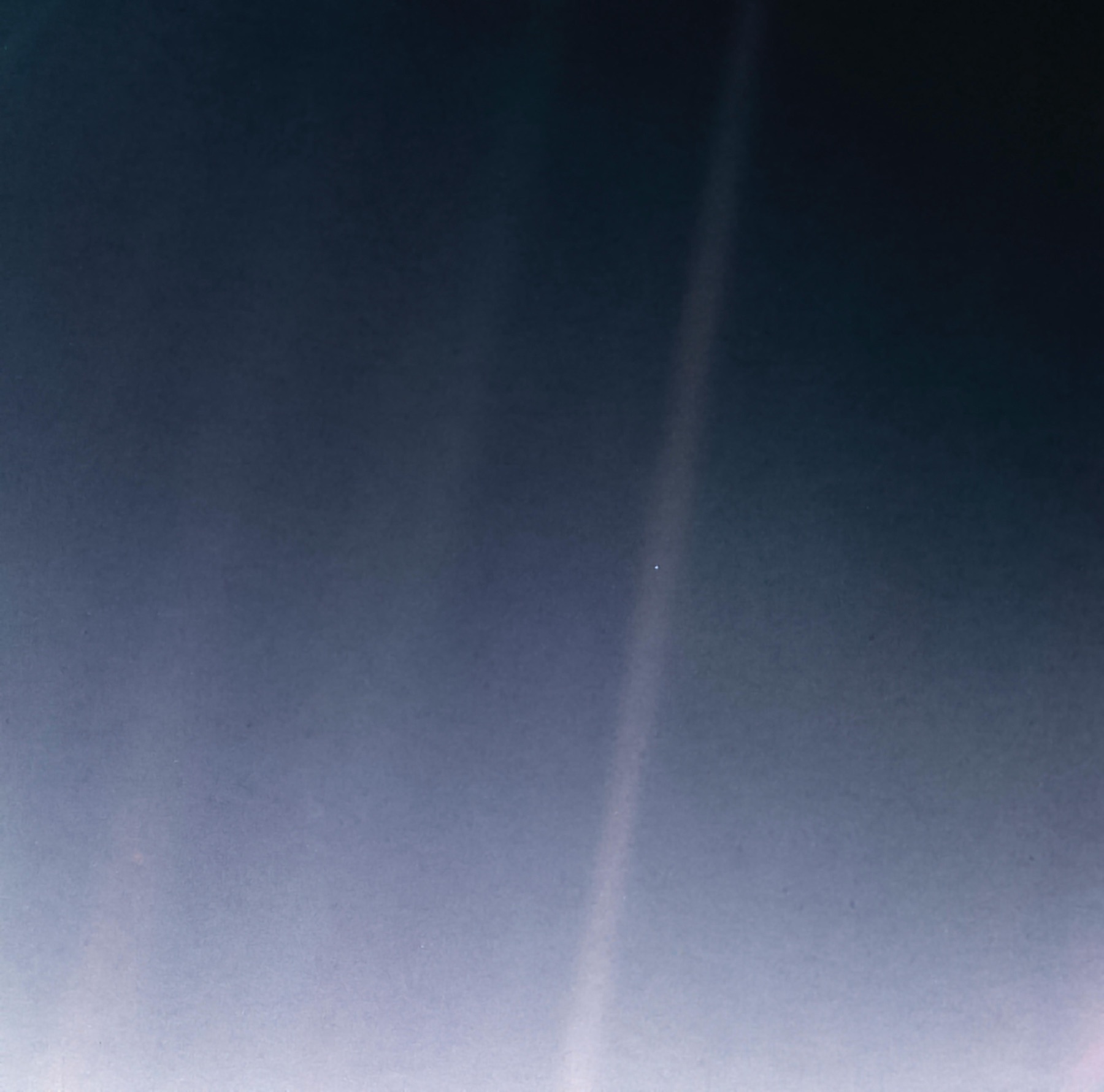 Voyager 1 image of Earth as a tiny pale blue speck inside a band of scattered sunlight