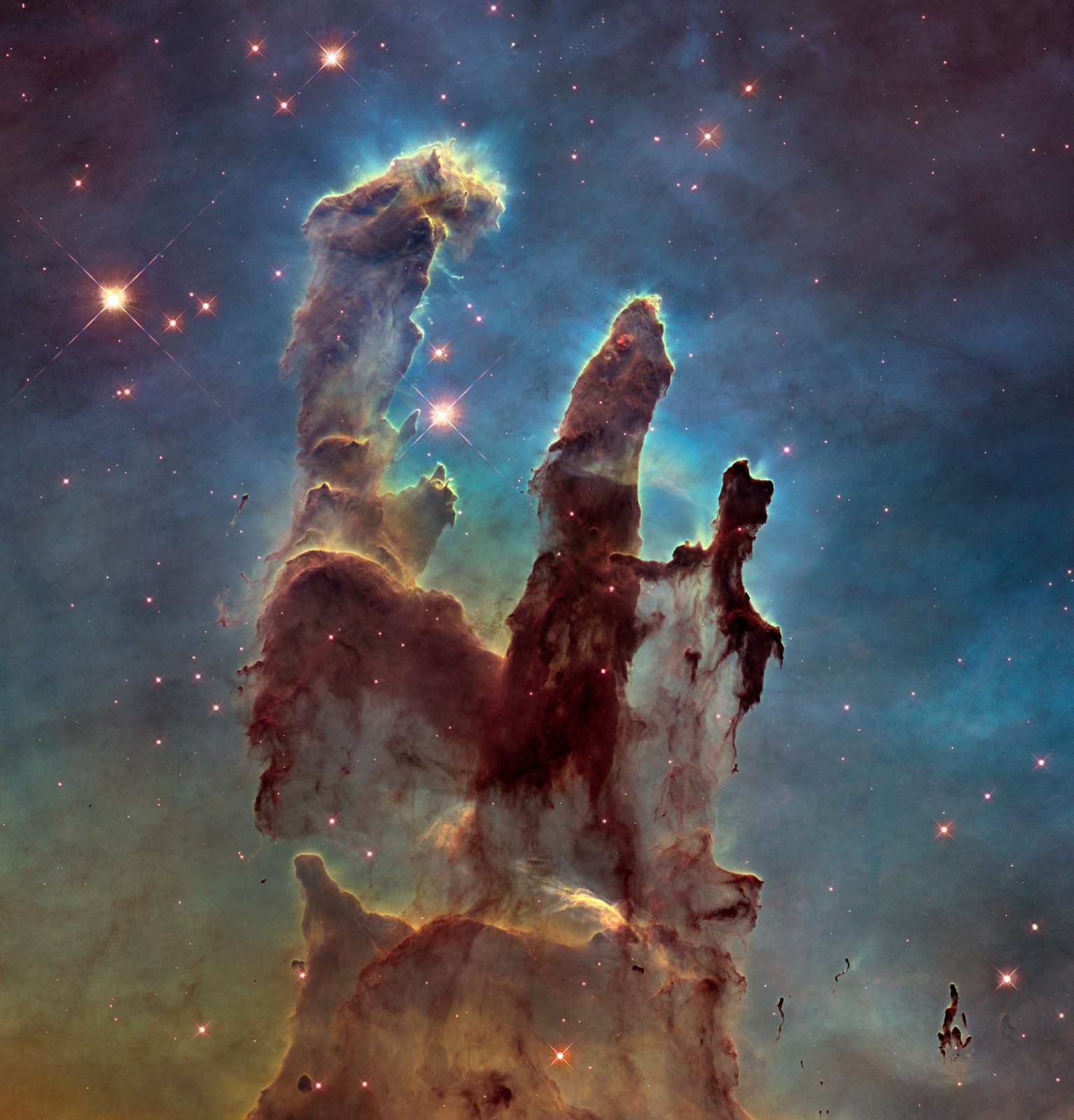 Webb near infrared view of the Pillars of Creation, a classic JWST vs Hubble comparison target, translucent brown and orange columns of gas studded with young red stars