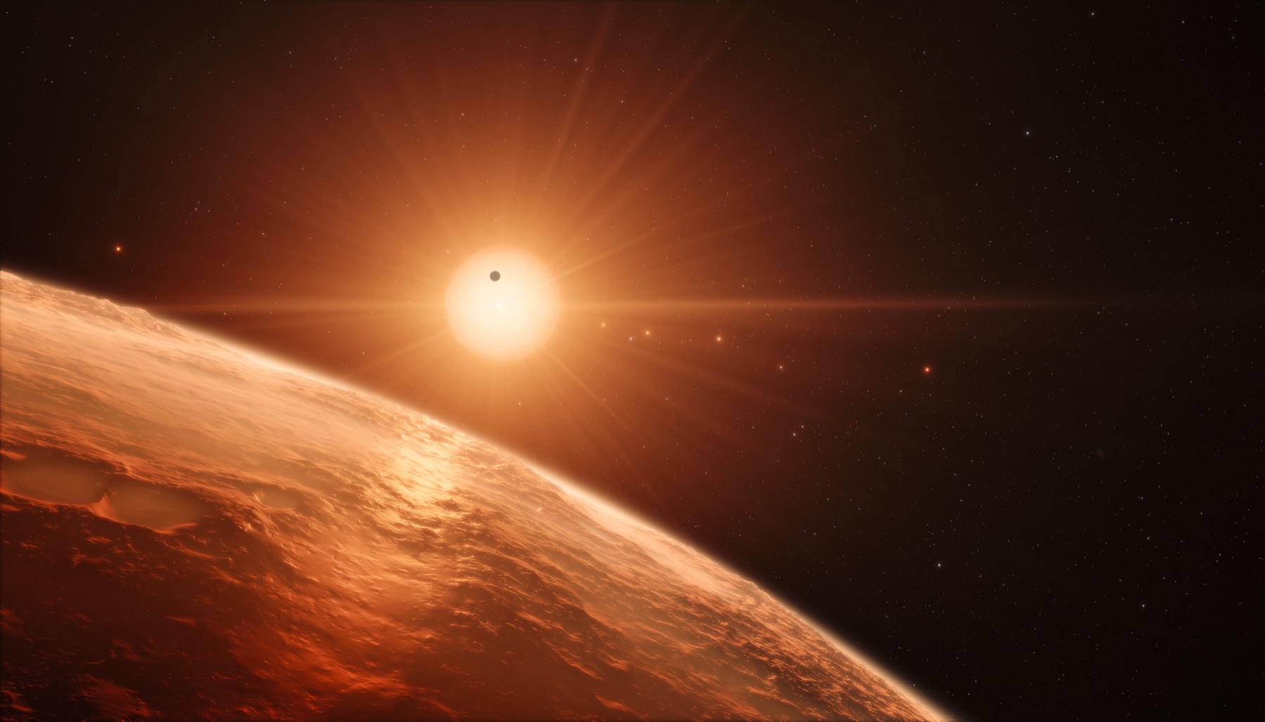 Artist impression of the view from the surface of one of the TRAPPIST-1 exoplanets, with the ultracool dwarf star glowing above the horizon