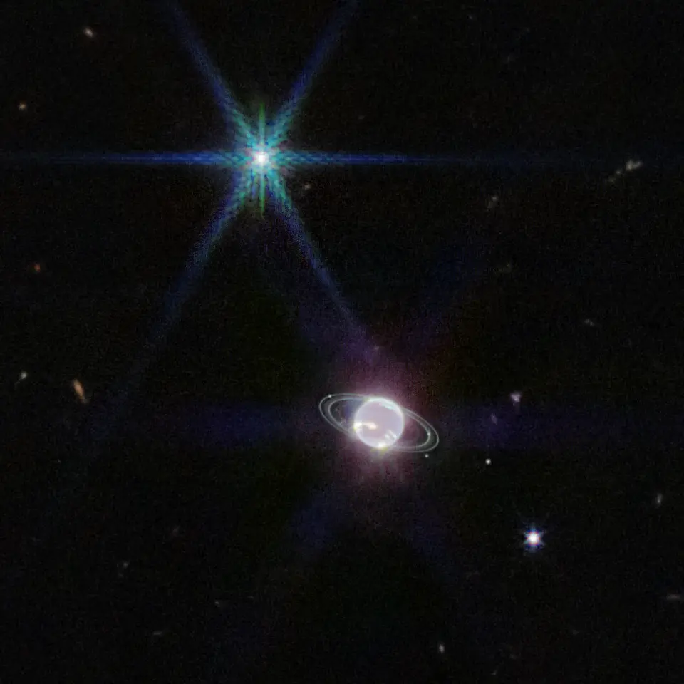 Neptune and its thin rings seen by Webb, with the moon Triton shining as a bright diffraction-spiked point.